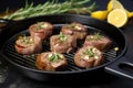 lamb medallions on a cast iron griddle coated with garlic and rosemary