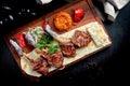 Lamb rack cooked on the grill with pita bread, bulgur and grilled vegetables on a wooden board. Turkish shashlik. Close up,