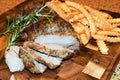 A lamb roast on a wooden board with crinkled fries