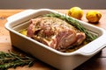 lamb shoulder with peeled garlic and rosemary in a baking dish