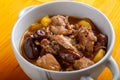 Lamb stewed with potatoes in spices and sauce with dates in a plate, close-up