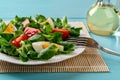 Lambs lettuce, egg and tomato salad close-up. Plate of cornsalad leaves, quartered tomato and boiled egg on a turquoise wooden