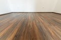 Laminated wood floor with white wall. Empty room with floating laminate in new apartmen