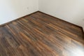 Laminated wood floor with white wall. Empty room with floating laminate in new apartmen