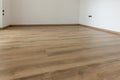 Laminated wood floor with white wall. Empty room with floating laminate in new apartmen