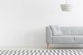 Grey couch in white minimal apartment interior with copy space on empty wall. Real photo Royalty Free Stock Photo