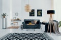 Lamp above patterned carpet in white living room interior with posters above green couch. Real photo Royalty Free Stock Photo