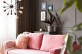 Lamp above pink settee with cushions in living room interior wit