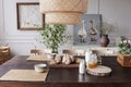 Lamp above wooden table with food and bowls in grey dining room interior with posters. Real photo Royalty Free Stock Photo