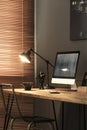 Lamp and desktop computer on desk in dark freelancer`s room inte Royalty Free Stock Photo