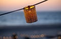 A lamp hangs on a wire against the background of a beach sunset