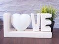 Lamp `Love` letters and artificial trees on a brown wooden table.