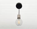 A lamp made with a tuned off light bulb. Chandelier in vintage style hanging on white wooden slatted ceiling. Lighting and