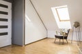 Lamp next to armchair on wooden floor in white attic interior wi