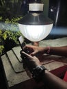 Using mobile phone in front of a old lamp and park