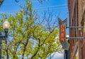 Lamp post and building with an Open sign against vibrant trees on a sunny day