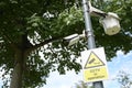 A lamp post with CCTV surveillance cameras installed against a backdrop of trees