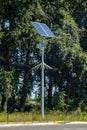 Lamp post with solar panel system on road with blue sky and trees. Autonomous street lighting using solar panels. Street lamp, on Royalty Free Stock Photo