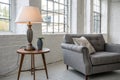 Lamp on table next to grey settee in white loft interior Royalty Free Stock Photo