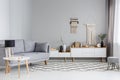 Lamp on table next to grey sofa in scandi living room interior w