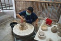 A ceramic potter is molding kaolin or China clay bowls on a rotating platform.