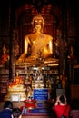 Tourist worshipping the sacred golden buddha image inside the old temple building Royalty Free Stock Photo