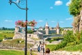 Lamppost decorated with pink flowers and walking people by Kamianets-Podilskyi fortress, selective focus