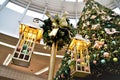 A pole with decorative chandeliers beside the Christmas tree