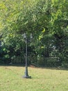 Lamppost with three lamps in green yard with trees