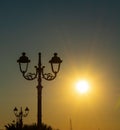 Lamppost under a shining sun in Alghero at sunset Royalty Free Stock Photo