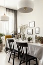 Lamps above black chairs at table in dining room interior with posters