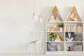 Lamps above white chair next to shelves with triangles in teenag