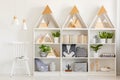 Lamps above white chair next to shelves with wooden triangles an