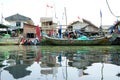 Fishing boats lean along the riverbank against a flat sky background