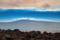 Lanai and shimmering ocean sandwiched by pinkish clouds above and volcanic rock below. Royalty Free Stock Photo