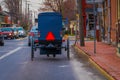 LANCASTER, USA - APRIL, 18, 2018: Outdoor view of the back of old fashioned Amish buggy with a horse riding at one side
