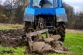 Land cultivation tractor plows the ground  a blue small tractor and a plow with three knives Royalty Free Stock Photo