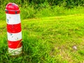 Land mark pole with white and red stripes in a grass landscape scene