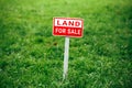 Land for sale plate sign, green grass background Royalty Free Stock Photo