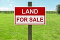 Land for sale sign in green grass field for housing development and construction Royalty Free Stock Photo