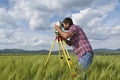 Land surveyor working with total station in the middle of wheat field Royalty Free Stock Photo