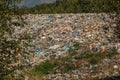 Landfill / dump site surrounded by green trees and mountains in background no logos / trademarks visible on dumped garbage Royalty Free Stock Photo