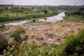 landfill surrounded by lush vegetation, with a river in the background