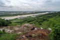landfill surrounded by lush vegetation, with a river in the background