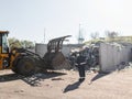 Landfill worker directing skid steer loader on the waste heap