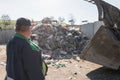 Landfill worker directing skid steer loader on the waste heap