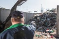 Landfill worker directing skid steer loader on the waste heap