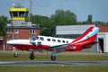 Landing Cessna 425 twin-engine plane with a tower in the background