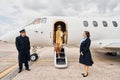 Landing is done. Airplane crew leads woman in yellow clothes from of a plane Royalty Free Stock Photo