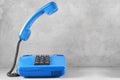 Landline blue phone on gray wall background Royalty Free Stock Photo